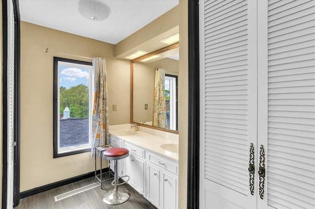 bathroom with wood finished floors, double vanity, and baseboards