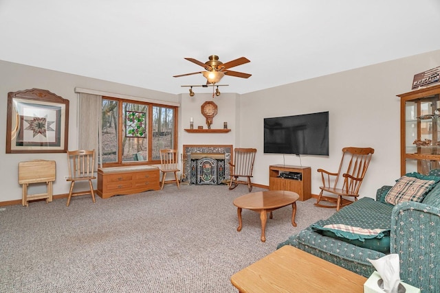 carpeted living room with baseboards, a ceiling fan, and a fireplace