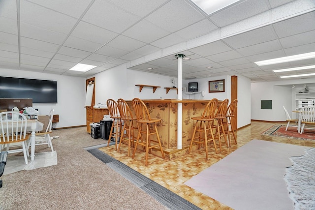 interior space featuring a bar, baseboards, and a paneled ceiling