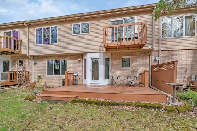 rear view of property featuring brick siding, a yard, and a balcony