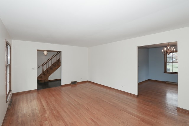 202 Heath Ct, Barrington, IL 60010 - unfurnished living room with an inviting chandelier, light wood-style flooring, visible vents, and stairway