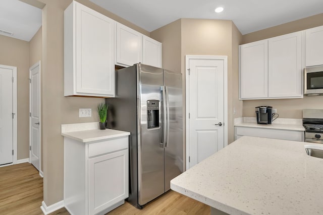 kitchen with white cabinets, recessed lighting, appliances with stainless steel finishes, and light wood-style flooring