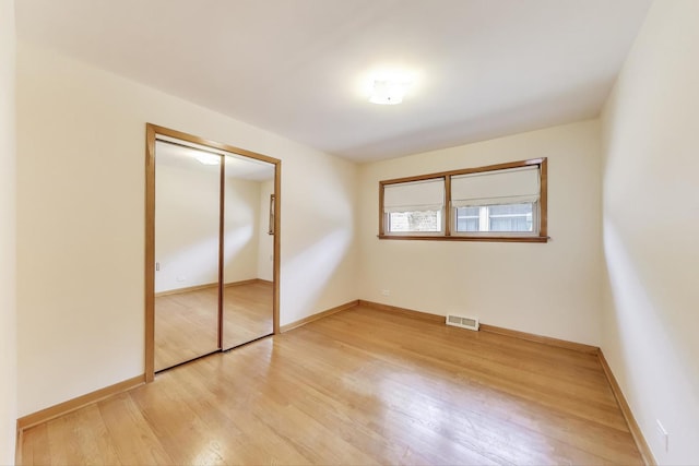 unfurnished bedroom featuring light wood-style flooring, baseboards, and a closet