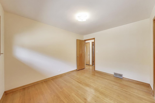 spare room featuring light wood-style floors and baseboards
