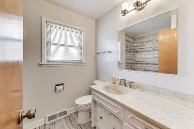 full bathroom with toilet, vanity, tiled shower, baseboards, and wood finished floors
