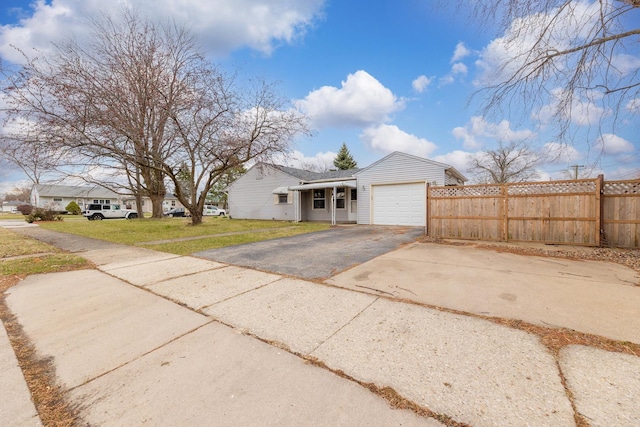 view of front of house featuring an attached garage, fence, a front yard, and aphalt driveway