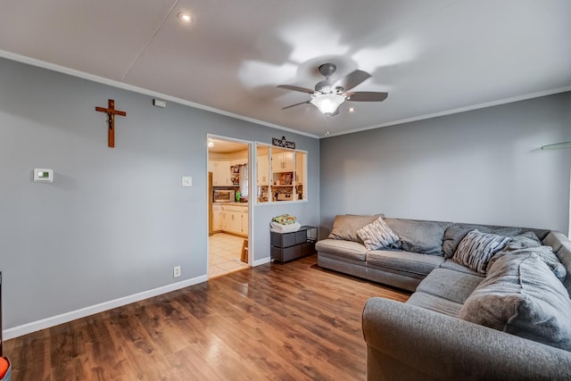 living area featuring crown molding, baseboards, ceiling fan, and wood finished floors