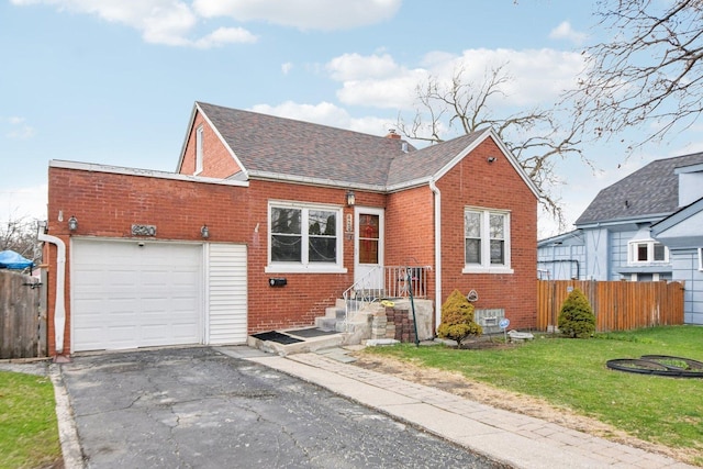 view of front of house featuring fence, roof with shingles, a front lawn, brick siding, and driveway