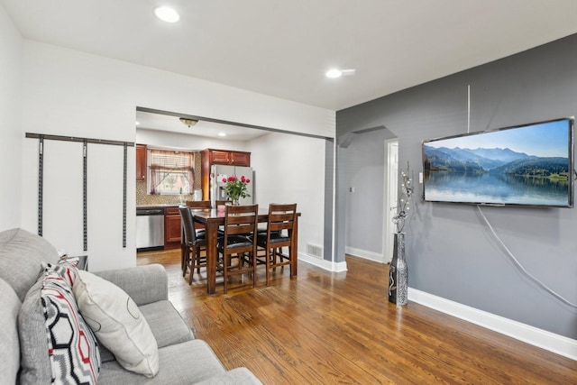 living room featuring arched walkways, recessed lighting, baseboards, wood finished floors, and visible vents