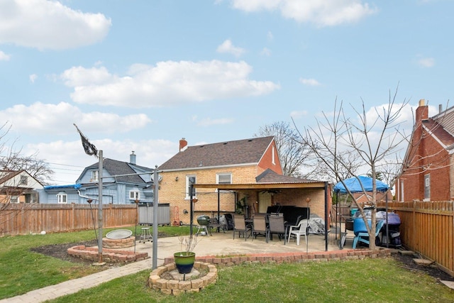 back of house featuring a patio, brick siding, a fenced backyard, and a lawn