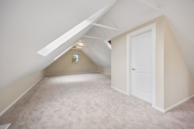 bonus room with carpet floors, baseboards, and vaulted ceiling with skylight
