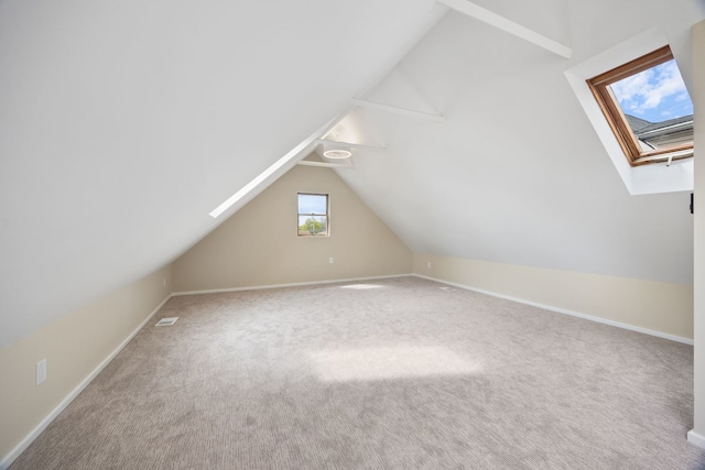 additional living space with vaulted ceiling with skylight, baseboards, and carpet flooring