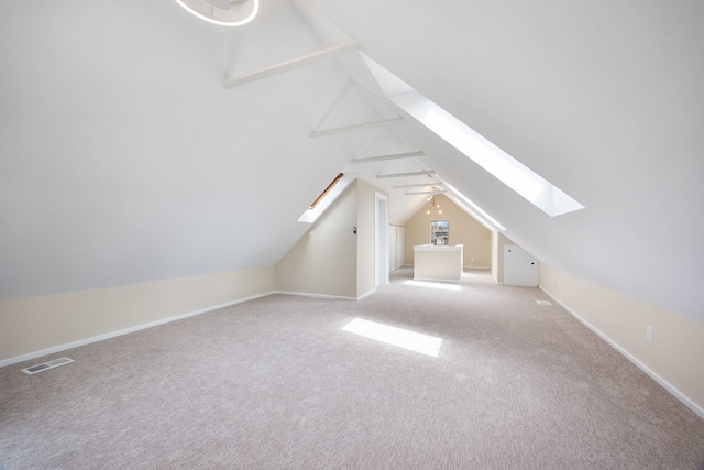 additional living space with visible vents, carpet flooring, baseboards, and vaulted ceiling with skylight