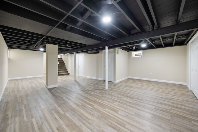 basement featuring baseboards, wood finished floors, and stairway