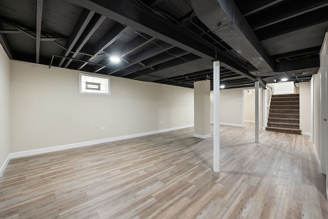 below grade area with baseboards, wood finished floors, and stairway