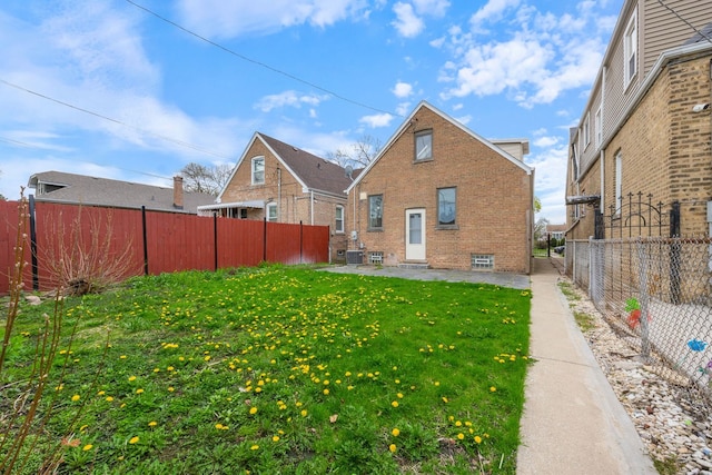 rear view of house with brick siding, a fenced backyard, a yard, and a patio