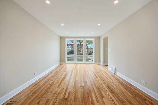 spare room featuring visible vents, baseboards, light wood-style floors, recessed lighting, and arched walkways