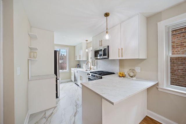 kitchen with a sink, marble finish floor, stainless steel appliances, baseboards, and white cabinetry