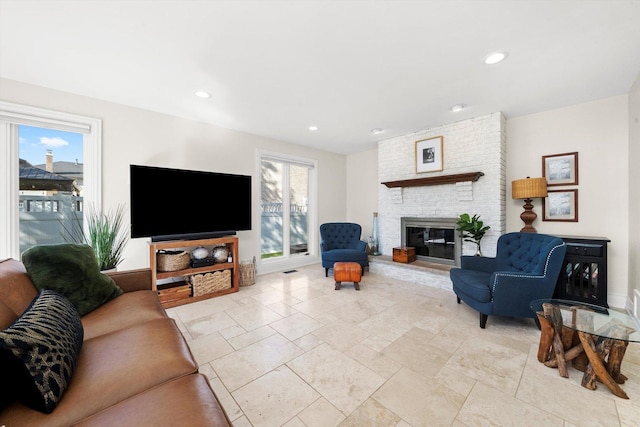 living room featuring recessed lighting, a brick fireplace, and stone tile floors