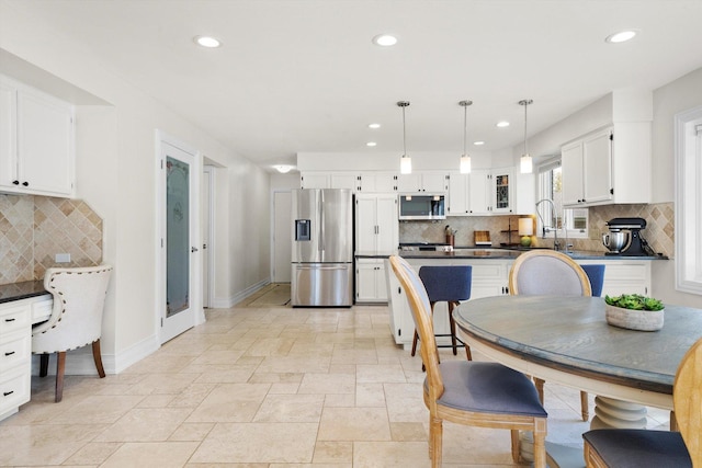 kitchen featuring appliances with stainless steel finishes, dark countertops, decorative backsplash, white cabinetry, and recessed lighting