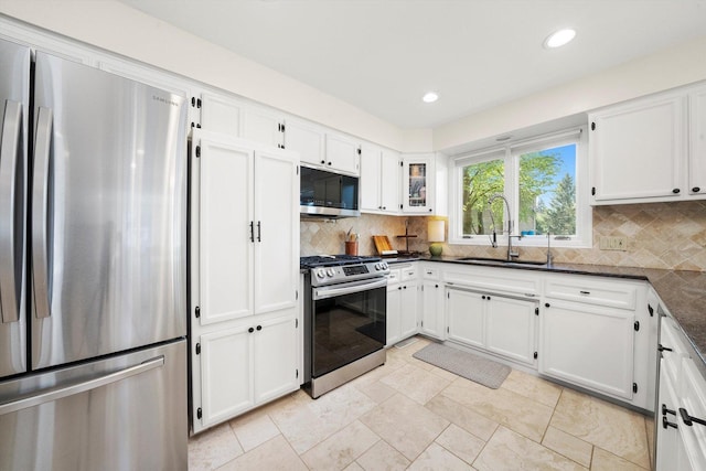 kitchen featuring appliances with stainless steel finishes, a sink, white cabinetry, backsplash, and recessed lighting