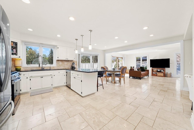 kitchen featuring a peninsula, dark countertops, tasteful backsplash, a breakfast bar area, and a sink
