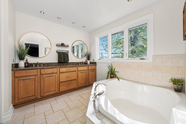 bathroom with a bath, recessed lighting, double vanity, and stone tile floors