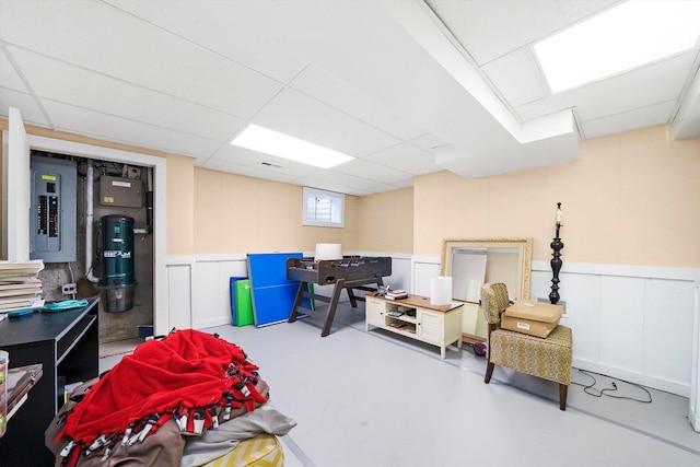 basement with electric panel, a paneled ceiling, a decorative wall, a wainscoted wall, and a central vacuum unit