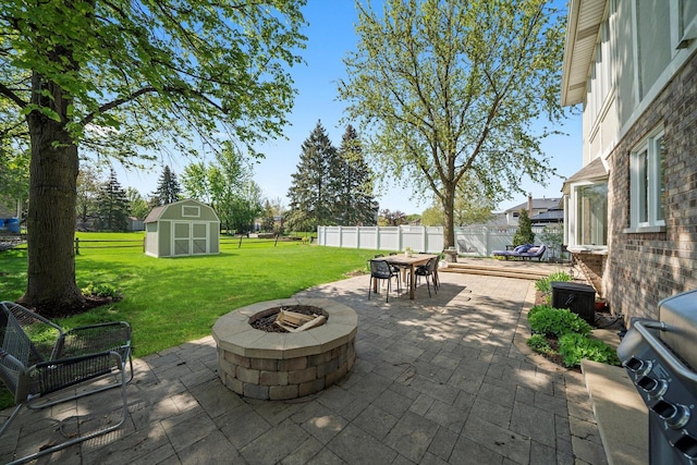 view of patio featuring a fire pit, a shed, outdoor dining space, and an outbuilding
