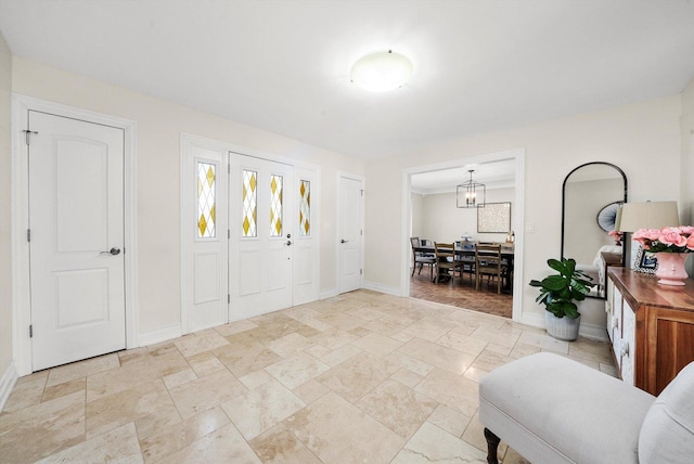 entrance foyer with baseboards, stone tile floors, and a chandelier