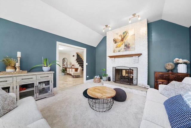carpeted living room with vaulted ceiling, a fireplace, stairs, and baseboards