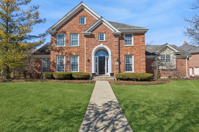 view of front facade with brick siding and a front yard