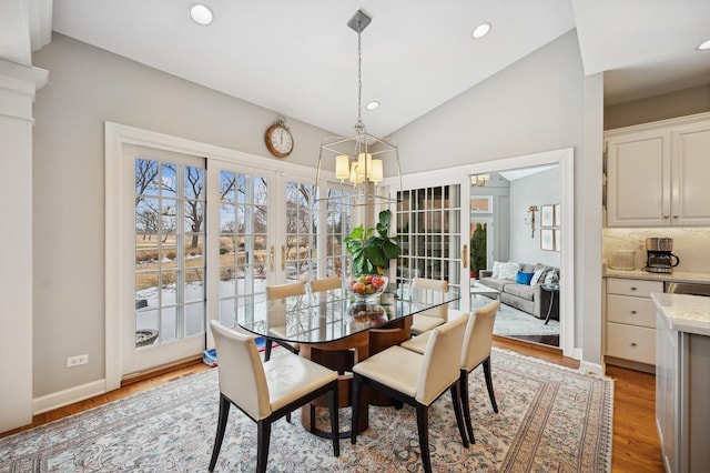 dining area with a chandelier, baseboards, lofted ceiling, light wood-style floors, and recessed lighting