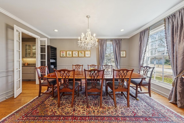 dining room with ornamental molding, light wood-style flooring, a chandelier, and a wealth of natural light