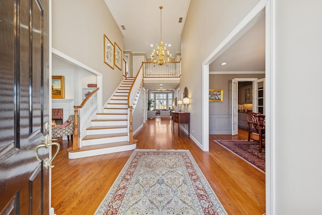 entryway featuring an inviting chandelier, baseboards, wood finished floors, a towering ceiling, and stairway