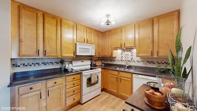 kitchen with a sink, dark countertops, white appliances, and tasteful backsplash