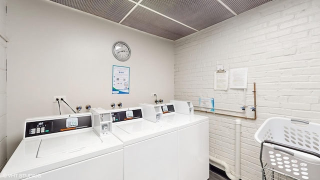 shared laundry area with brick wall and washing machine and clothes dryer