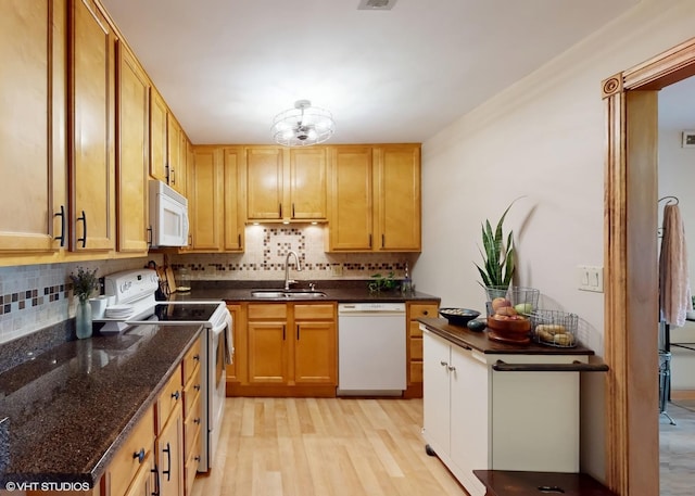 kitchen with a sink, tasteful backsplash, white appliances, and light wood-style flooring