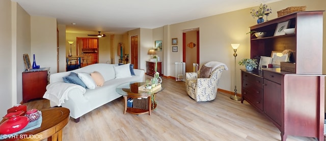living area with light wood-type flooring, a ceiling fan, and baseboards