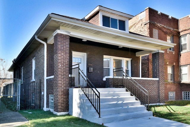 bungalow-style home with brick siding, fence, and covered porch
