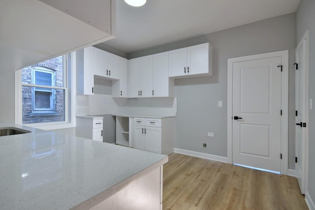 kitchen featuring light wood-style floors, baseboards, light stone countertops, and white cabinetry