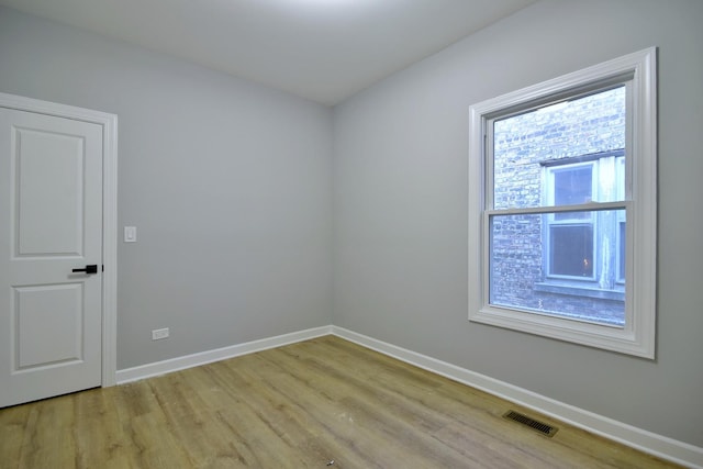 empty room with baseboards, light wood finished floors, and visible vents