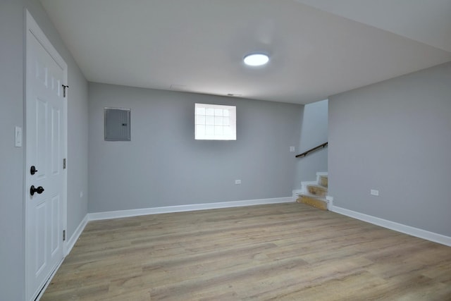basement with light wood-type flooring, baseboards, electric panel, and stairs