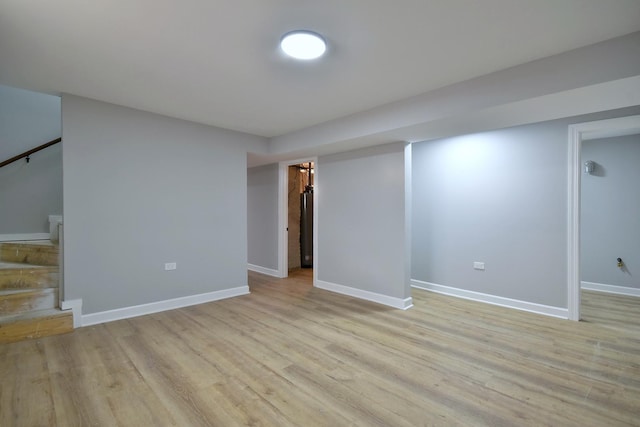 finished below grade area with baseboards, stairway, and light wood-style floors