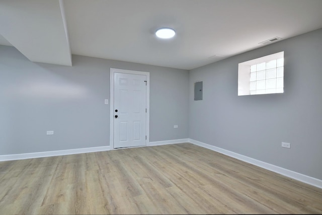 spare room with baseboards, electric panel, light wood-style flooring, and visible vents