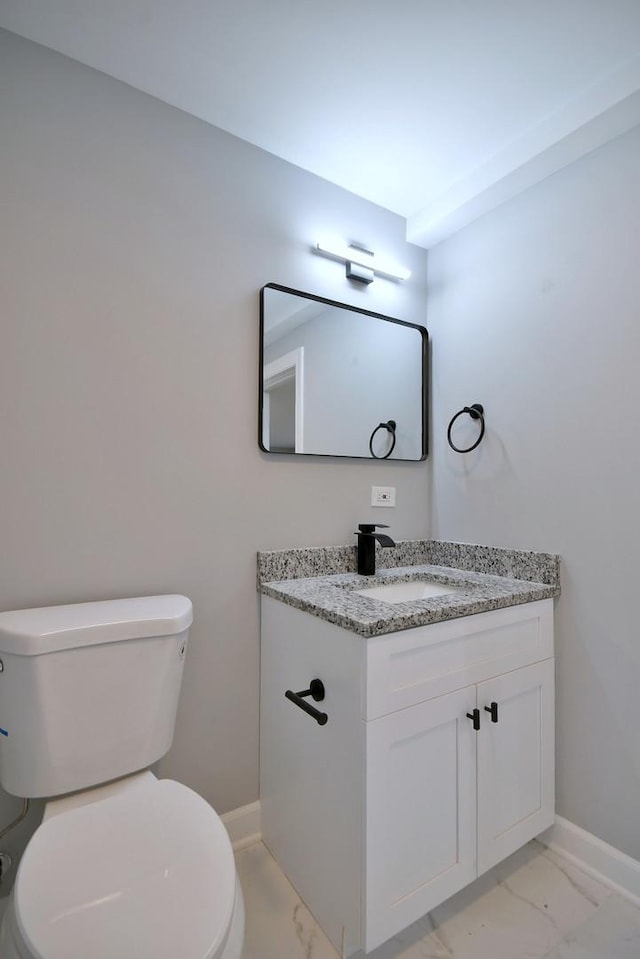 half bath featuring baseboards, vanity, toilet, and marble finish floor