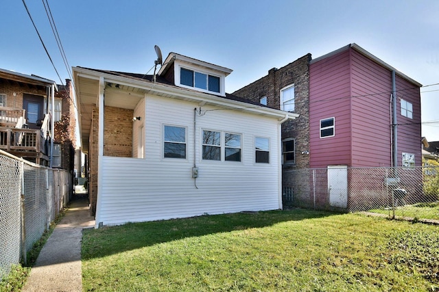 rear view of house featuring a lawn and fence