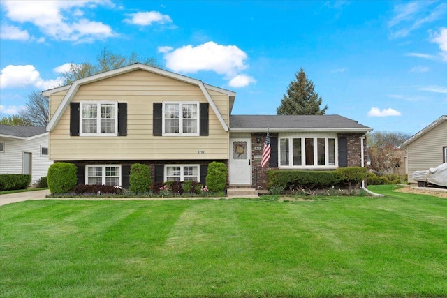 tri-level home with a front yard, brick siding, and a gambrel roof
