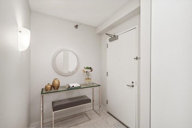 interior space featuring baseboards and marble finish floor