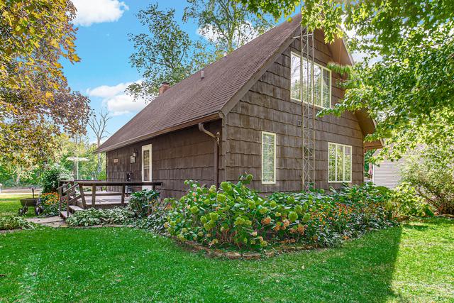 view of home's exterior with a lawn, a shingled roof, a wooden deck, and a chimney